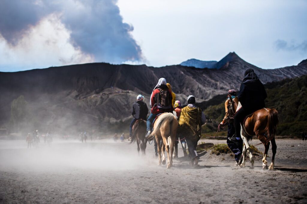 Adventurous group riding horses in dusty landscape near Mount Bromo, East Java.